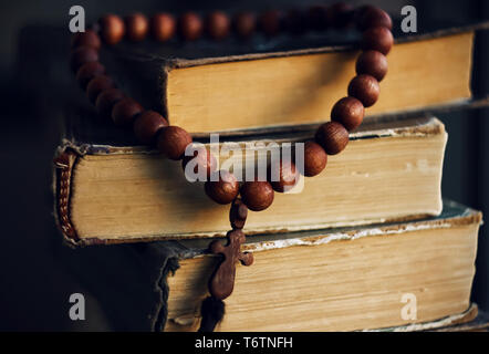 Auf dem alten schäbigen Schriften liegen gelassen Rosenkranz aus Mahagoni mit einem geschnitzten Symbol des Kreuzes. Stockfoto