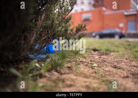 Blue big Kunststoff Flasche auf dem Boden liegend in Baum in einem Park Wald geworfen, die nicht recycelt - Abfall und Verschmutzung der Stadt und Natur - Verfallen Stockfoto