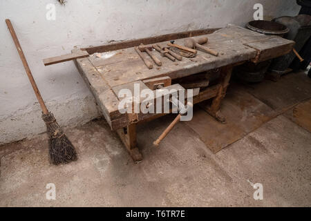 Traditionelle Besen neben einem alten Workbench von einem Zimmermann in seiner Werkstatt in der alpinen Region in Österreich Stockfoto