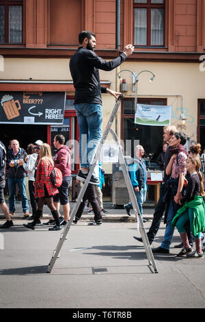 Berlin, Deutschland - 01.Mai 2019: Mann auf Leiter mit Handy auf der Street Parade am Tag der Arbeit in Berlin. Stockfoto