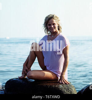 Deutsche Fictitious character Christiane Rücker posiert mit einem Stein im Meer sterben, Ca. 1970er. Die deutsche Schauspielerin Christiane Rücker stellt auf einem Felsen im Meer, Ca. 70er Jahre. Stockfoto