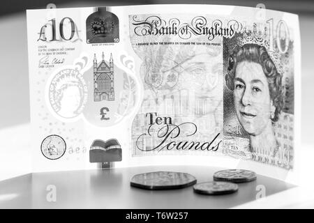 Nahaufnahme einer Stück neue £ 10 Banknoten- und Pence Münzen. Zehn Pfund Sterling mit Porträt Königin Elizabeth II. Stockfoto