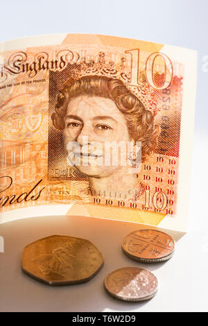 Nahaufnahme einer Stück neue £ 10 Banknoten- und Pence Münzen. Zehn Pfund Sterling mit Porträt Königin Elizabeth II. Stockfoto