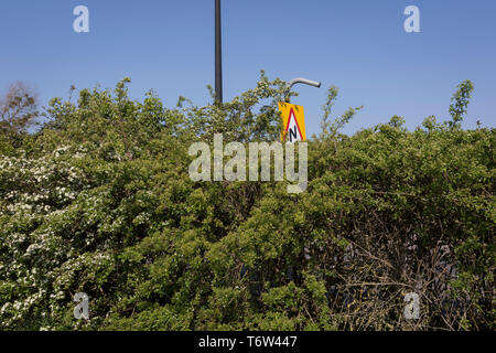 Ein dreieckiges Warnzeichen für Double Bend über die Hecke auf einem Parkplatz in Nailsea gesehen, am 21. April 2019, in Nailsea, North Somerset, England Stockfoto