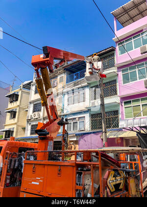 Elektriker auf dem Lkw Kran nach oben versetzt zu prüfen elektrische power line in Soi ManSri, PomPrab, Bangkok, Thailand, und reparieren Sie sie. Stockfoto