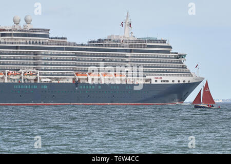 Die riesigen, Cunard Line, MS QUEEN VICTORIA, Nahe einem kleinen Segelboot, wie Sie Segel aus Southampton, UK, für Hamburg. 28. April 2019. Stockfoto