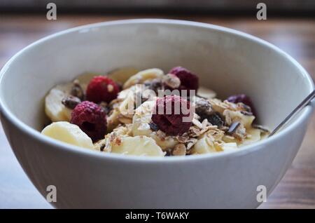 Guten Morgen Frühstück, Müsli in eine Schüssel mit Bananen und Himbeeren Stockfoto