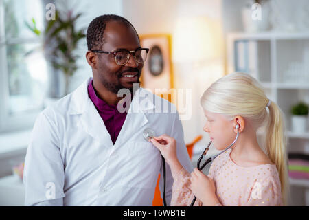 Lustig Mädchen spielen mit Arzt während der Verwendung Stethoskop Stockfoto