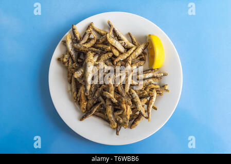 Gebratene Sprotten mit Zitrone in Weiß auf Blau Tabelle Stockfoto