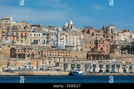 Historische Kalksteinbastionen und -Gebäude säumen die Uferpromenade von Valletta mit Blick auf den tiefblauen Grand Harbour Stockfoto