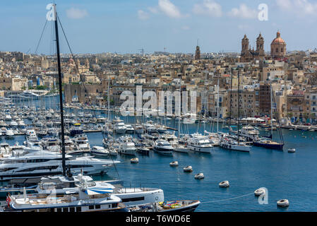 Luxusyachten und Vergnügungsboote, die in Dockyard Creek im Grand Harbour von Valletta festgemacht sind, blicken auf die Basilika der Geburt Mariens, Senglea Stockfoto