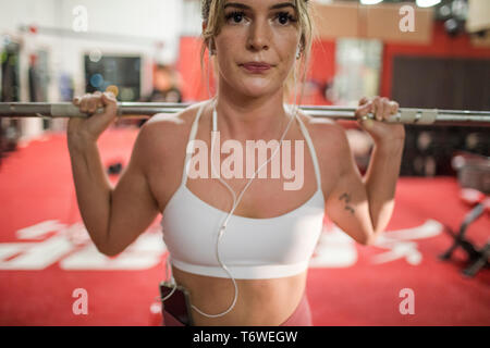 7/8-Ansicht von attraktiven Frau heben Barbell im Gymnasium Stockfoto