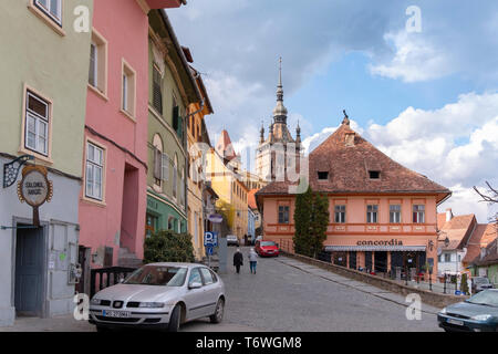 SIGHISOARA, Rumänien - April 9, 2019: Bunte Dächer und Häuser im Zentrum von Sighisoara. Street Scene an einem sonnigen Tag mit älteren Menschen zu Fuß Stockfoto