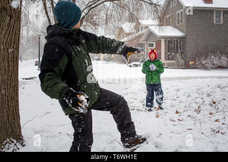 Ein Vater Winde oben mit einem schneeball Sohn zu werfen Stockfoto