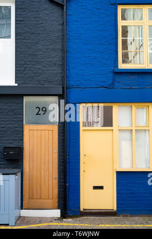 Gelbe Tür in einem blau gestrichenen Haus neben grau gestrichenen Haus, St. Lukes Mews, Notting Hill, West London, England Stockfoto