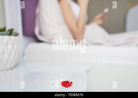 Kranke Frau mit Kopfschmerzen unter der Decke sitzen. Krankes Mädchen mit saisonalen Infektion Grippe im Bett lag und mit einer Decke im Bett mit dem Lügen Stockfoto