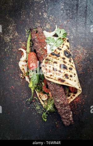 Traditionelle Adana Kebap am Spieß mit Tomaten und Joghurt auf einem fladenbrot Stockfoto