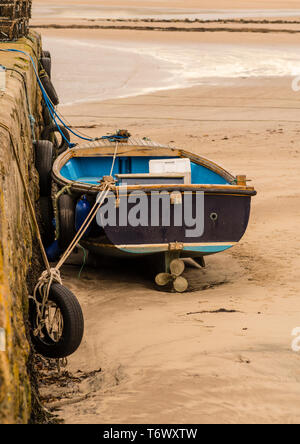 Ein kleines Boot Strandete am Sandstrand günstig auf die hafenmauer bei Ebbe. Stockfoto