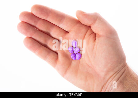 Topview des Palm der kaukasischen Hand mit einem kleinen Haufen von lila Armee Schädel, Ecstasy, MDMA, Amphetaminen oder Medikamente wie ein Schädel geformt Stockfoto