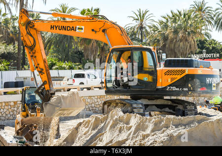 CANNES, Frankreich - April 2019: Bagger arbeiten auf einem Haufen Sand verwendet wird am Strand in Cannes für die Ferienzeit zu verbessern. Stockfoto