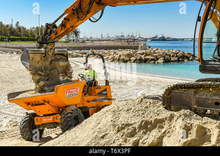 CANNES, Frankreich - April 2019: Der Schaufel von einem Bagger drop Sand in einen Kipper den Strand zu verbessern in Cannes für die Ferienzeit bereit Stockfoto