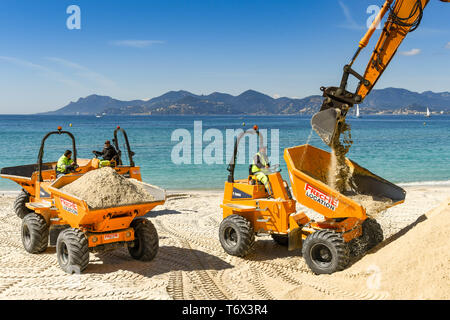 CANNES, Frankreich - April 2019: Der Schaufel von einem Bagger drop Sand in einen Kipper den Strand zu verbessern in Cannes für die Ferienzeit bereit Stockfoto