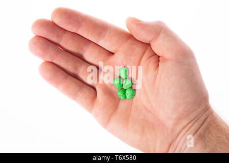 Topview palm kaukasischen männliche Hand mit einem kleinen Haufen grün Schädel, Ecstasy, MDMA, Amphetaminen oder Medikamente wie ein Schädel geprägt. Stockfoto