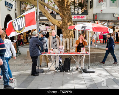 München, Bayern, Deutschland. Zum 2. Mai, 2019. Der Neonazi NPD organisierte eine Tabelle in einer der am meisten befahrenen Stadtteile Münchens - die Fußgängerzone in der Innenstadt, wo Kunden, Gäste und Mitarbeiter. Hinter dem Tisch war Münchner Stadtrat Karl Richter, Teil der neonazistischen Gruppe Buergerinitiativ Auslaender Stopp (Bürger Initiative Stopp Ausländer) und Renate Werlberger der NPD. Beide Parteien sind weithin als ein und dieselbe und von Richter in Bezug auf die Ideologie und die Mitgliedschaft bestätigt akzeptiert. Das Duo angezeigt auch Plakate mit ''Migration'' tötet, Stockfoto