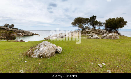 Bäume und Felsen in der Nähe der kleinen Bucht von Sveti Blaz (Insel Cres, Kroatien) an einem bewölkten Tag im Frühling Stockfoto