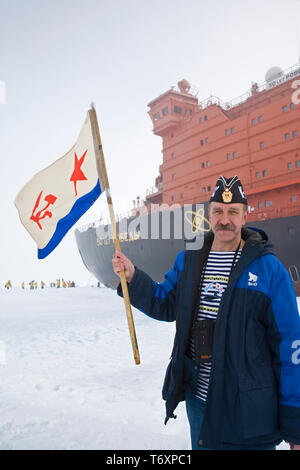 Russische Sailor mit Sowjetischen Flagge steht neben der weltweit größte nukleare Icebreaker 50 Jahre Sieg am Nordpol. Stockfoto