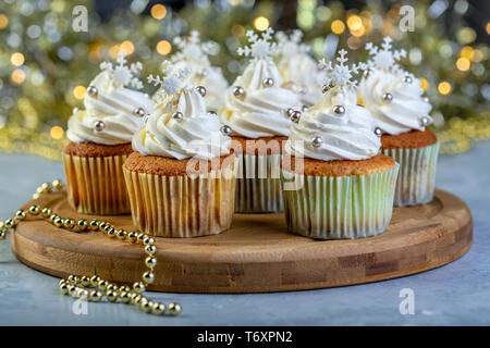 Cupcakes mit Sahne und Weihnachtsschmuck. Stockfoto