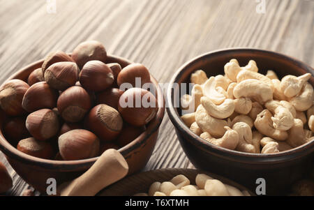 Schalen mit verschiedenen Muttern auf hölzernen Tisch Stockfoto