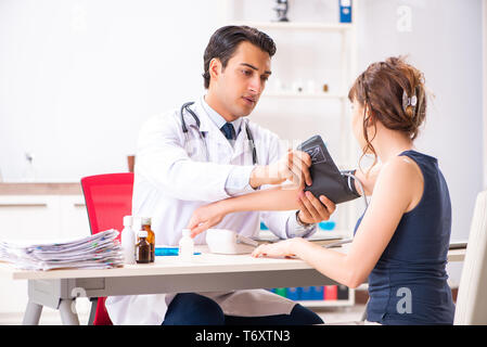 Der junge Arzt prüfen Frau Blutdruck Stockfoto