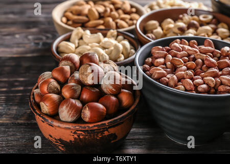Schalen mit verschiedenen Muttern auf hölzernen Tisch Stockfoto