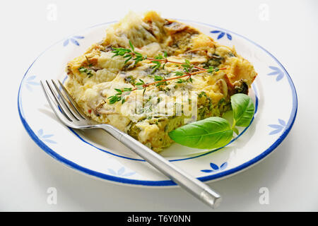 Frisch gebackene Champignon Käse quiche Slice auf blaue und weiße Platte im Querformat, Thymian und Basilikum garnieren. Stockfoto