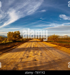 Eine unbefestigte Straße, die zu den fernen Bergen am Horizont in der Wüste von Arizona. Stockfoto