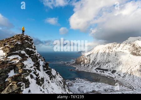 Weibliche Wanderer sieht von Volandstinden in die Ferne, hinter Ramberg, Lofoten, Norwegen Flakstadoya, Stockfoto