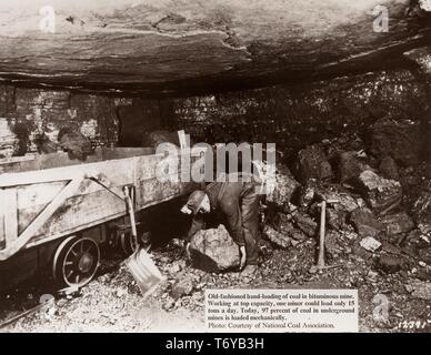 Ein Bergmann, am Ende einer kleinen, dunklen Passage in einer bituminösen Mine, beugt sich ein großes Stück Kohle in eine offene Bahn Auto, 1920 zu heben. Mit freundlicher National Coal Association/US Department of Energy. () Stockfoto