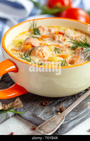Cremige Suppe mit Lachs und Gemüse in eine Schüssel geben. Stockfoto