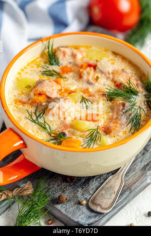 Cremige Suppe mit Lachs und Gemüse in eine Schüssel geben. Stockfoto