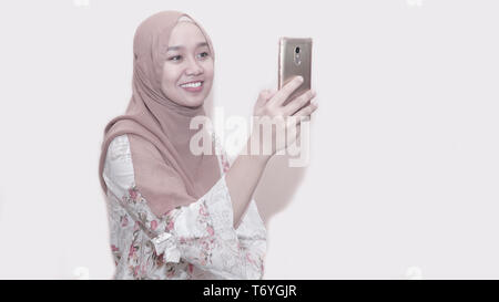 Portrait von asiatischen muslimische Frau mit Kopftuch oder hijab Sie Ihr Smartphone unter selfie, Anruf- und Videokonferenz - Bild Stockfoto