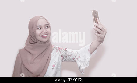 Portrait von asiatischen muslimische Frau mit Kopftuch oder hijab Sie Ihr Smartphone unter selfie, Anruf- und Videokonferenz - Bild Stockfoto