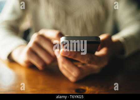 Frau mit Smartphone auf hölzernen Tisch im Café. Nahaufnahme mit sozialen Netzwerken Konzept Stockfoto