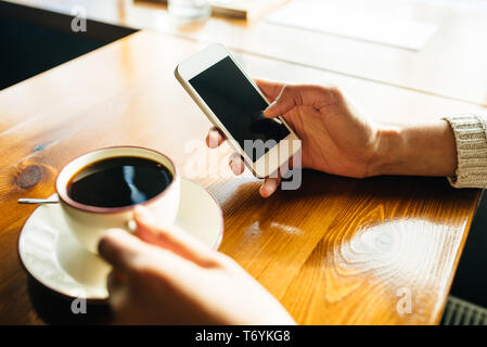 Frau mit Smartphone auf hölzernen Tisch im Café. Nahaufnahme mit sozialen Netzwerken Konzept Stockfoto