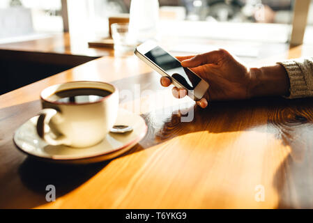 Frau mit Smartphone auf hölzernen Tisch im Café. Nahaufnahme mit sozialen Netzwerken Konzept Stockfoto