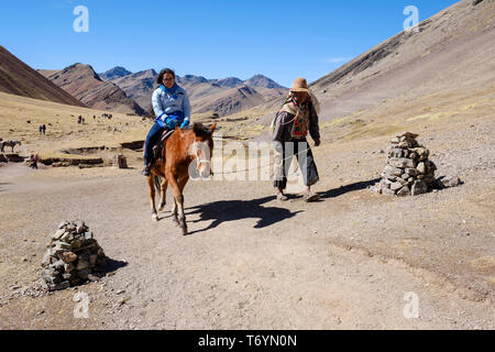 Touristen ein Pferd reiten zu den eindrucksvollen Rainbow Berg in Los Andes von Peru zu erhalten Stockfoto