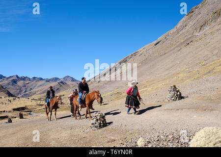 Touristen ein Pferd reiten zu den eindrucksvollen Rainbow Berg in Los Andes von Peru zu erhalten Stockfoto