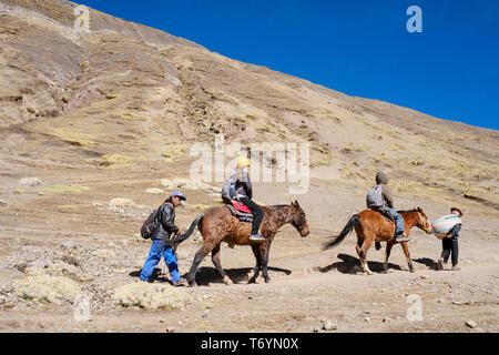 Touristen ein Pferd reiten zu den eindrucksvollen Rainbow Berg in Los Andes von Peru zu erhalten Stockfoto