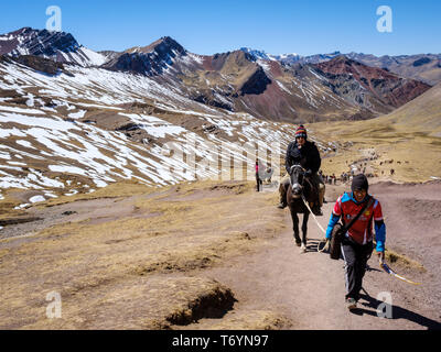 Touristen ein Pferd reiten zu den eindrucksvollen Rainbow Berg in Los Andes von Peru zu erhalten Stockfoto