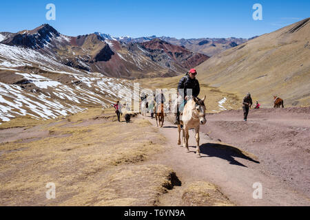 Touristen ein Pferd reiten zu den eindrucksvollen Rainbow Berg in Los Andes von Peru zu erhalten Stockfoto